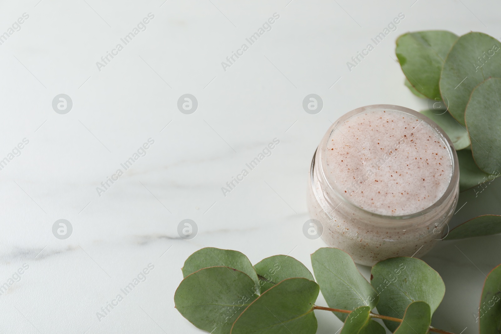 Photo of Natural body scrub and eucalyptus on white table. Space for text