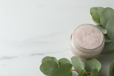 Photo of Natural body scrub and eucalyptus on white table. Space for text