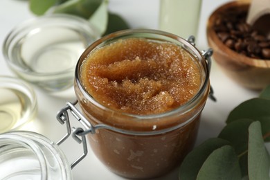 Photo of Natural body scrub and ingredients on white table, closeup