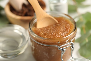 Photo of Natural body scrub and ingredients on white table, closeup