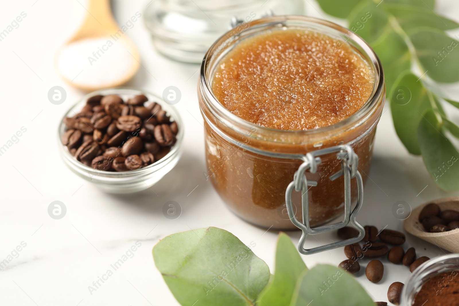 Photo of Natural body scrub and ingredients on white table, closeup