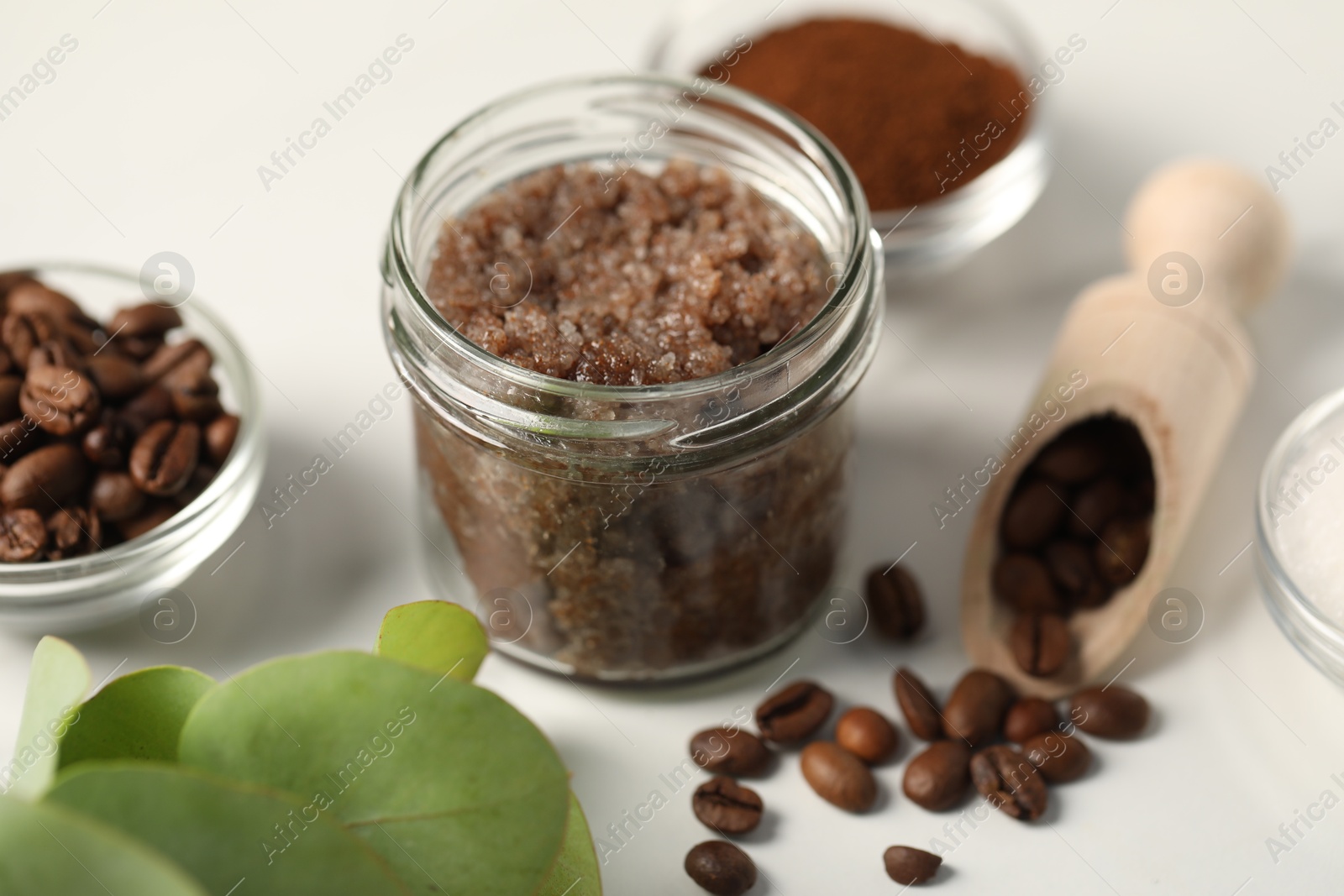 Photo of Natural body scrub and ingredients on white table, closeup