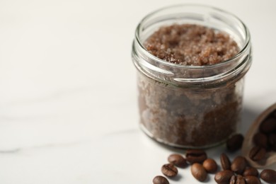 Photo of Natural body scrub and coffee beans on white table, closeup. Space for text