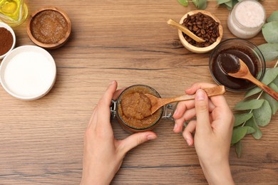 Photo of Woman making natural body scrub at wooden table, top view
