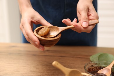 Photo of Woman making natural body scrub at wooden table, closeup