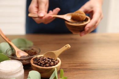 Photo of Woman making natural body scrub at wooden table, closeup
