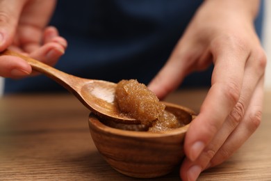 Photo of Woman with natural body scrub at wooden table, closeup