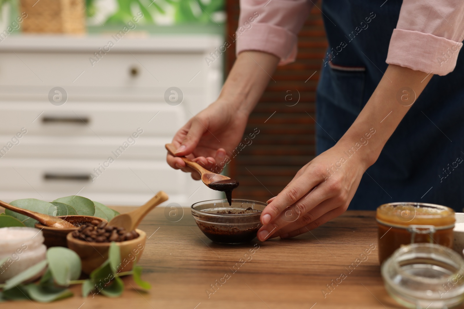Photo of Woman making natural body scrub at wooden table, closeup