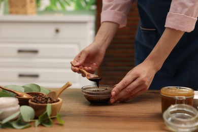 Photo of Woman making natural body scrub at wooden table, closeup