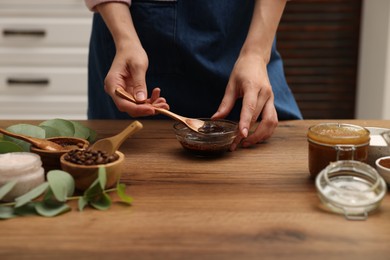 Photo of Woman making natural body scrub at wooden table, closeup