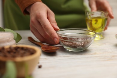 Photo of Woman making natural body scrub at white wooden table, closeup