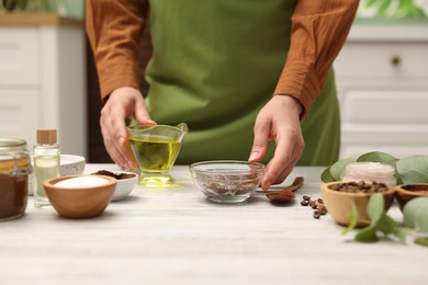 Photo of Woman making natural body scrub at white wooden table, closeup
