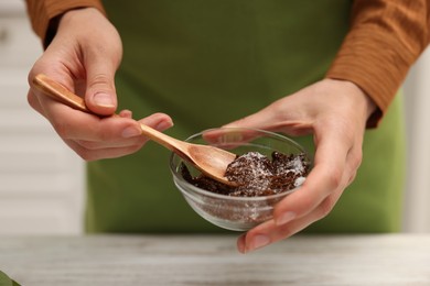 Photo of Woman making natural body scrub at white wooden table, closeup