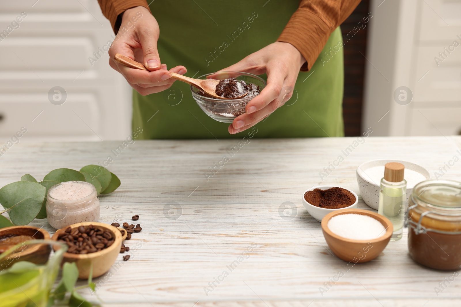 Photo of Woman making natural body scrub at white wooden table, closeup