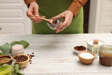 Photo of Woman making natural body scrub at white wooden table, closeup