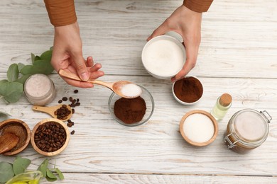 Photo of Making natural scrub. Woman adding sugar into bowl at white wooden table, top view