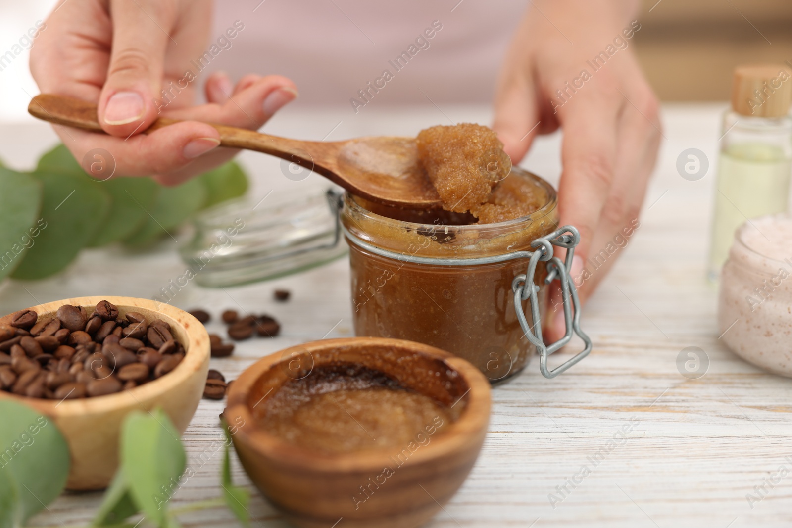 Photo of Woman making natural body scrub at white wooden table, closeup