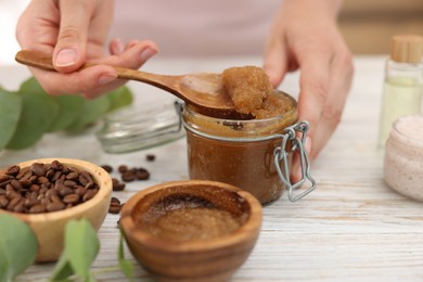 Photo of Woman making natural body scrub at white wooden table, closeup