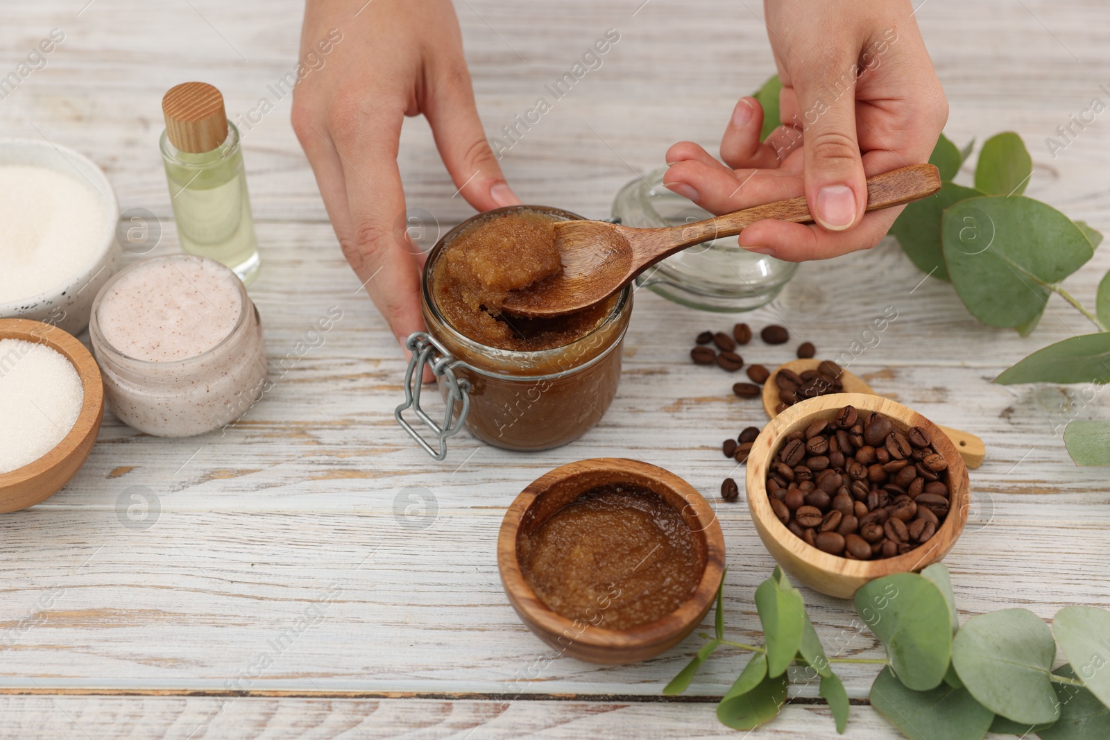 Photo of Woman making natural body scrub at white wooden table, closeup