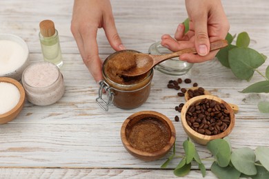 Photo of Woman making natural body scrub at white wooden table, closeup