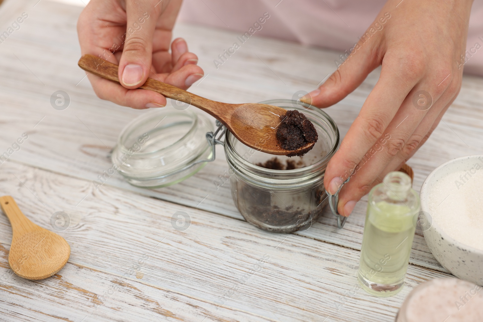 Photo of Woman making natural body scrub at white wooden table, closeup
