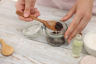 Photo of Woman making natural body scrub at white wooden table, closeup