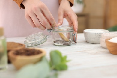 Photo of Woman making natural body scrub at white wooden table, closeup