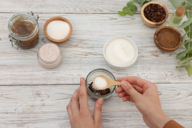 Photo of Making natural scrub. Woman adding sugar into jar at white wooden table, top view