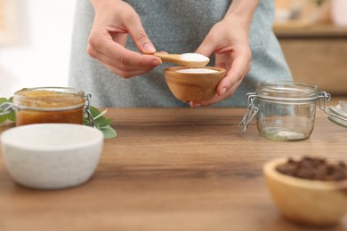 Photo of Making natural scrub. Woman with sugar at wooden table, closeup