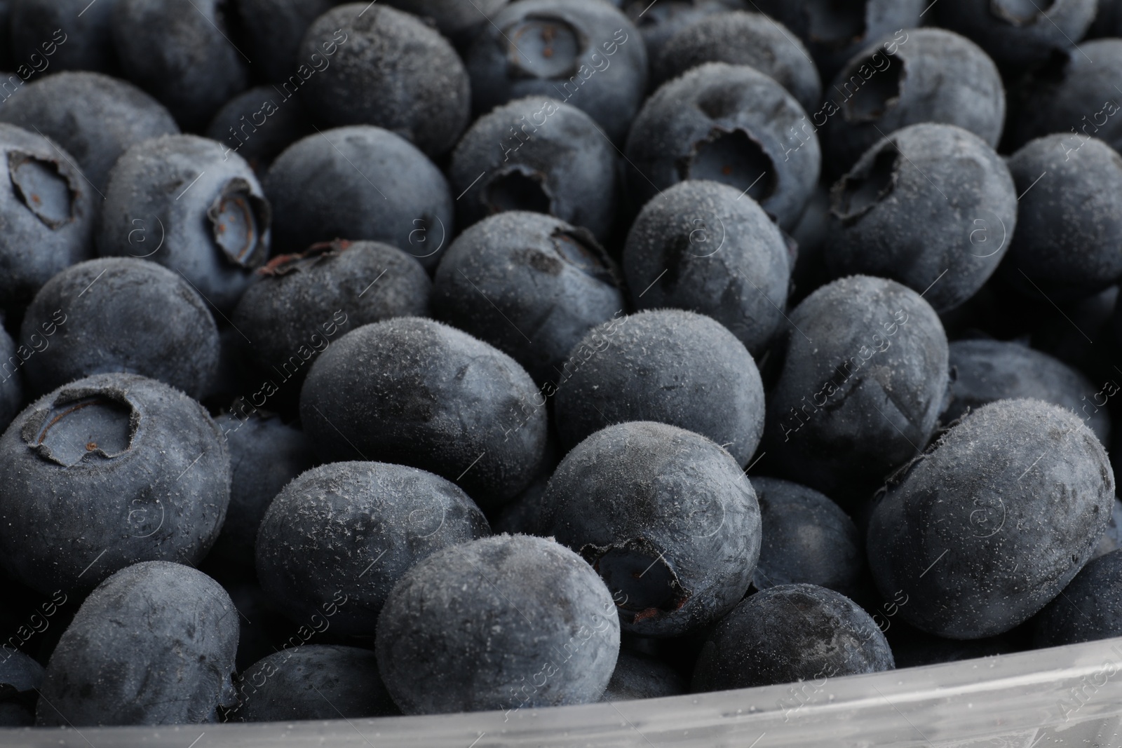 Photo of Heap of frozen blueberries in container, closeup