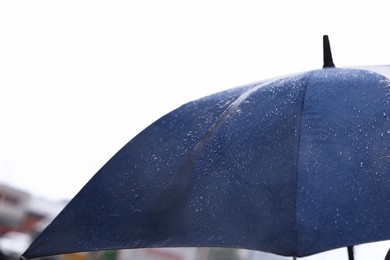 Photo of Blue umbrella under heavy rain outdoors, closeup