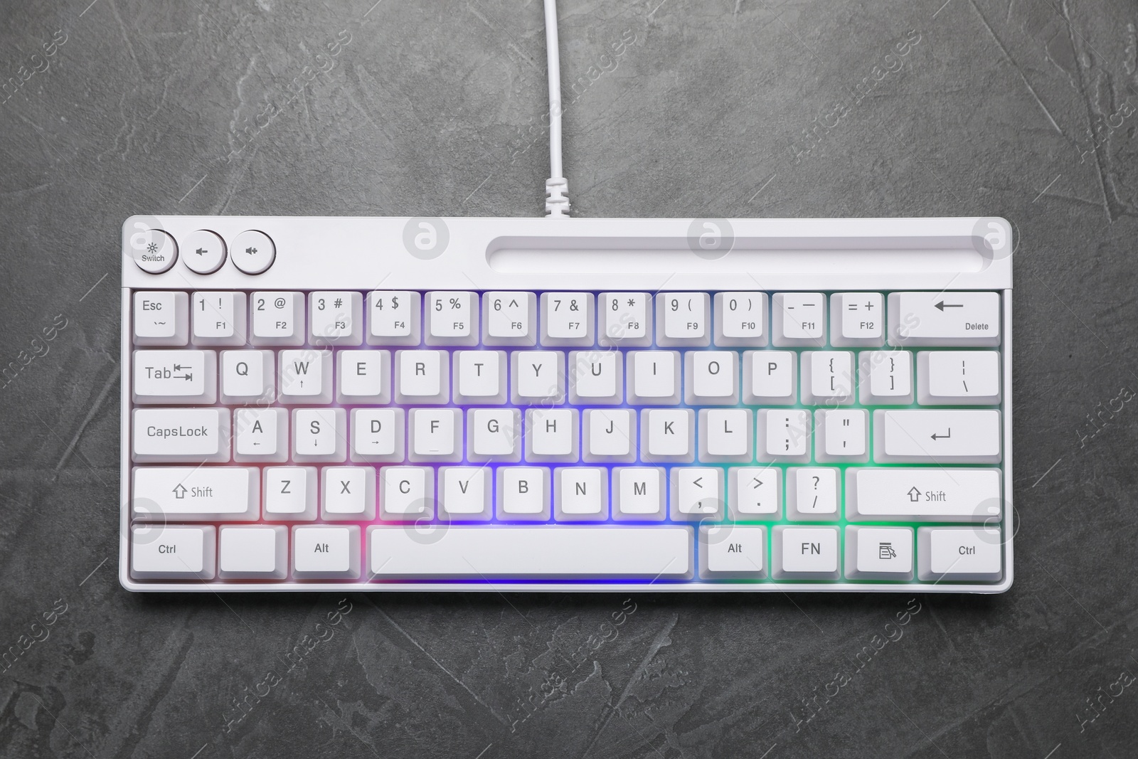 Photo of Modern white keyboard with RGB lighting on grey table, top view