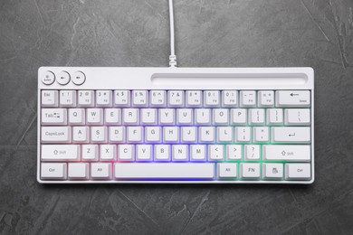Photo of Modern white keyboard with RGB lighting on grey table, top view