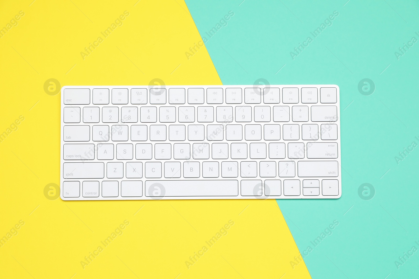 Photo of Modern white wireless keyboard on color background, top view