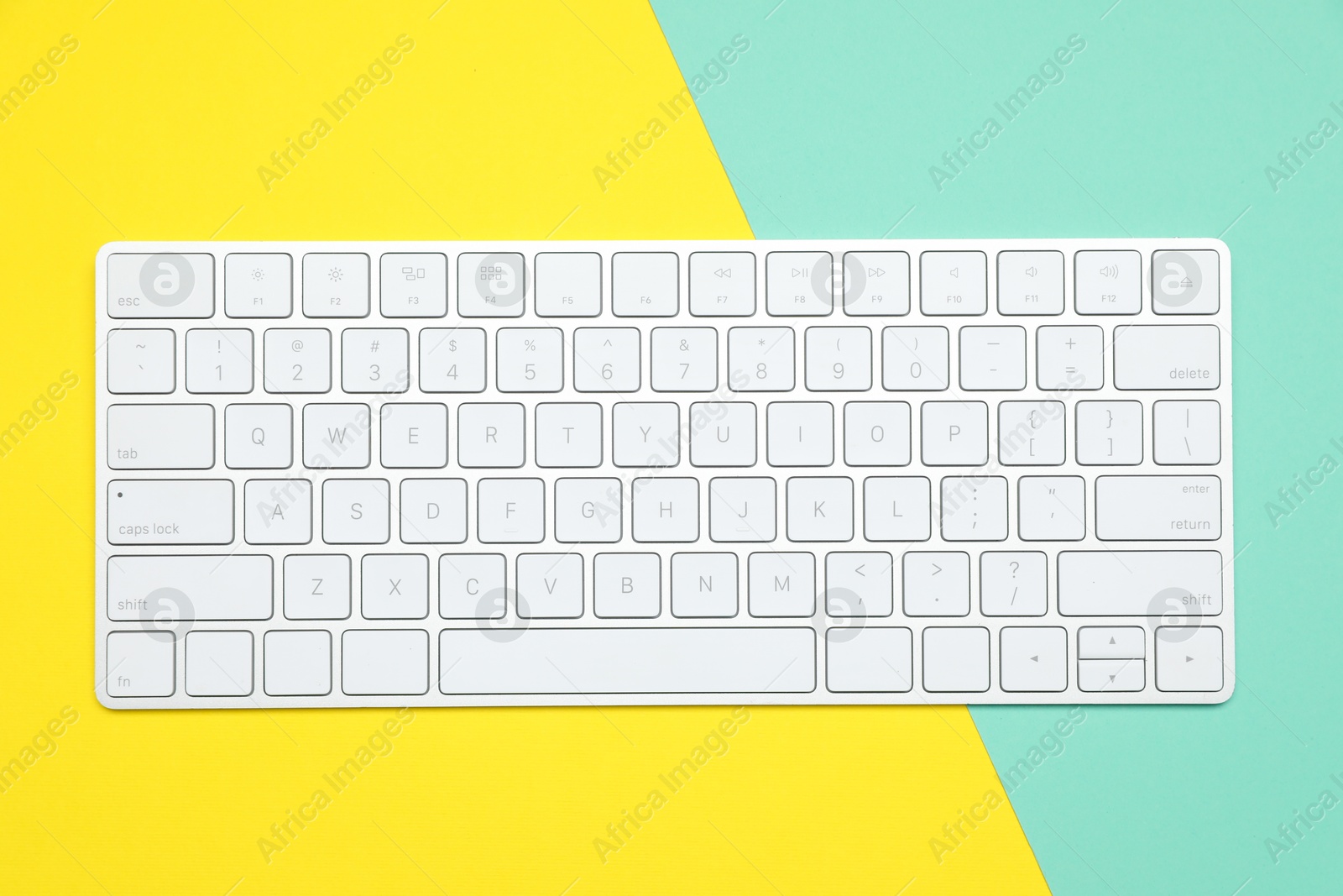 Photo of Modern white wireless keyboard on color background, top view