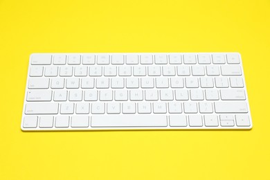 Photo of Modern white wireless keyboard on yellow background