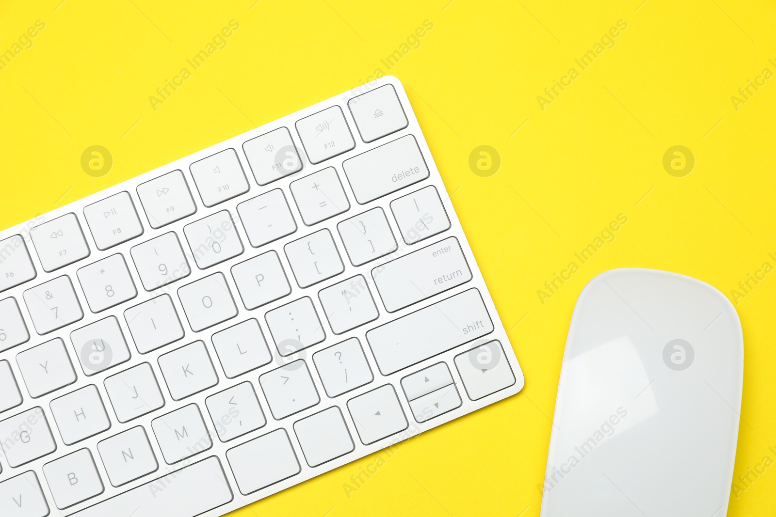 Photo of Modern white wireless keyboard and mouse on yellow background, top view