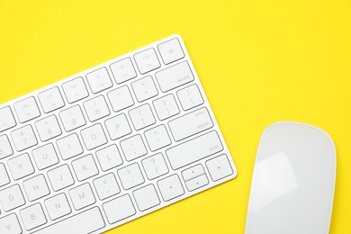 Photo of Modern white wireless keyboard and mouse on yellow background, top view