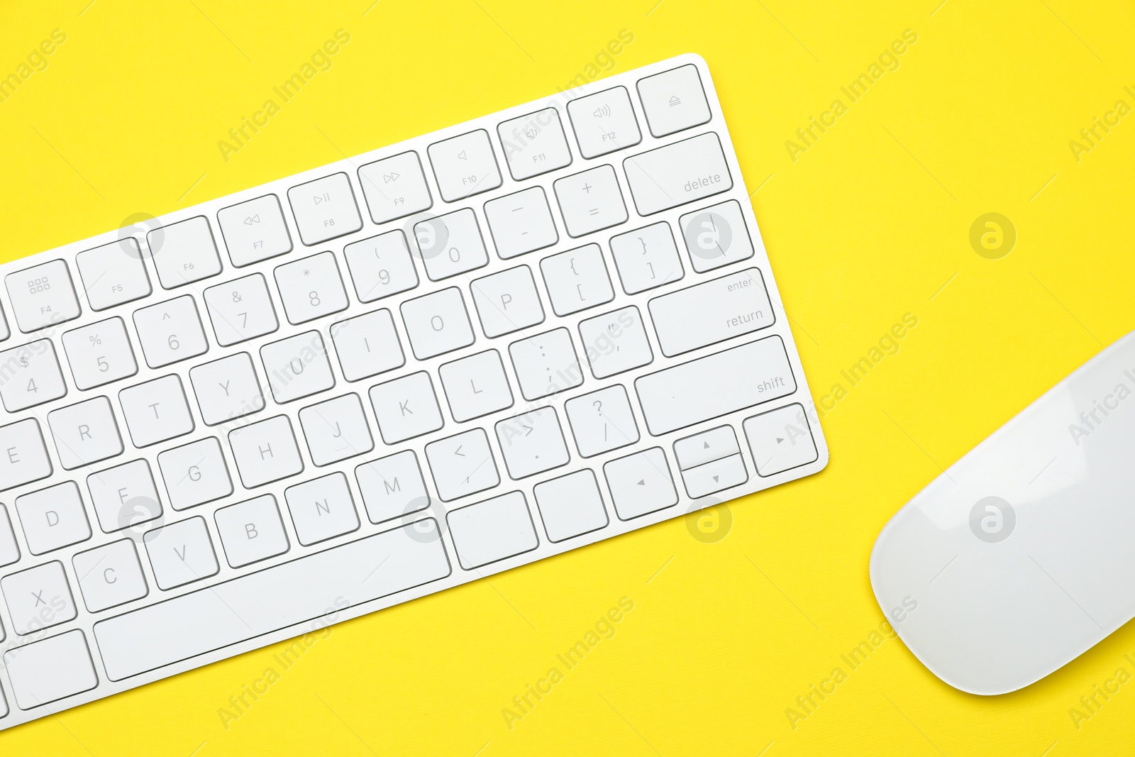 Photo of Modern white wireless keyboard and mouse on yellow background, top view