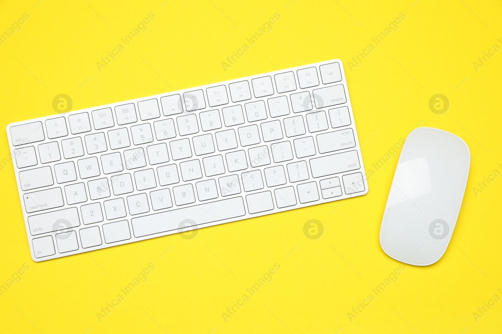 Photo of Modern white wireless keyboard and mouse on yellow background, top view