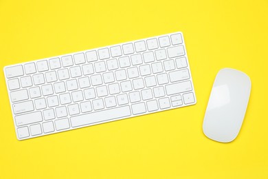 Photo of Modern white wireless keyboard and mouse on yellow background, top view
