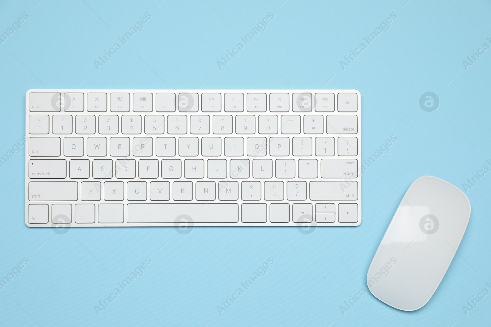Photo of Modern white wireless keyboard and mouse on light blue background, top view