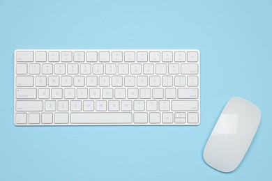 Photo of Modern white wireless keyboard and mouse on light blue background, top view