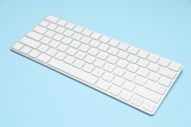 Photo of Modern white wireless keyboard on light blue background