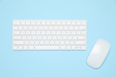Photo of Modern white wireless keyboard and mouse on light blue background, top view