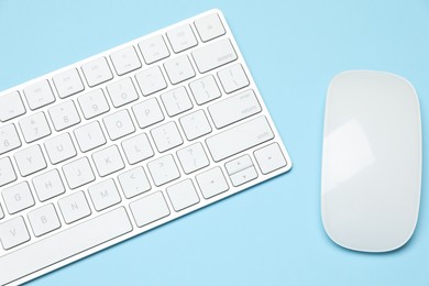 Photo of Modern white wireless keyboard and mouse on light blue background, top view