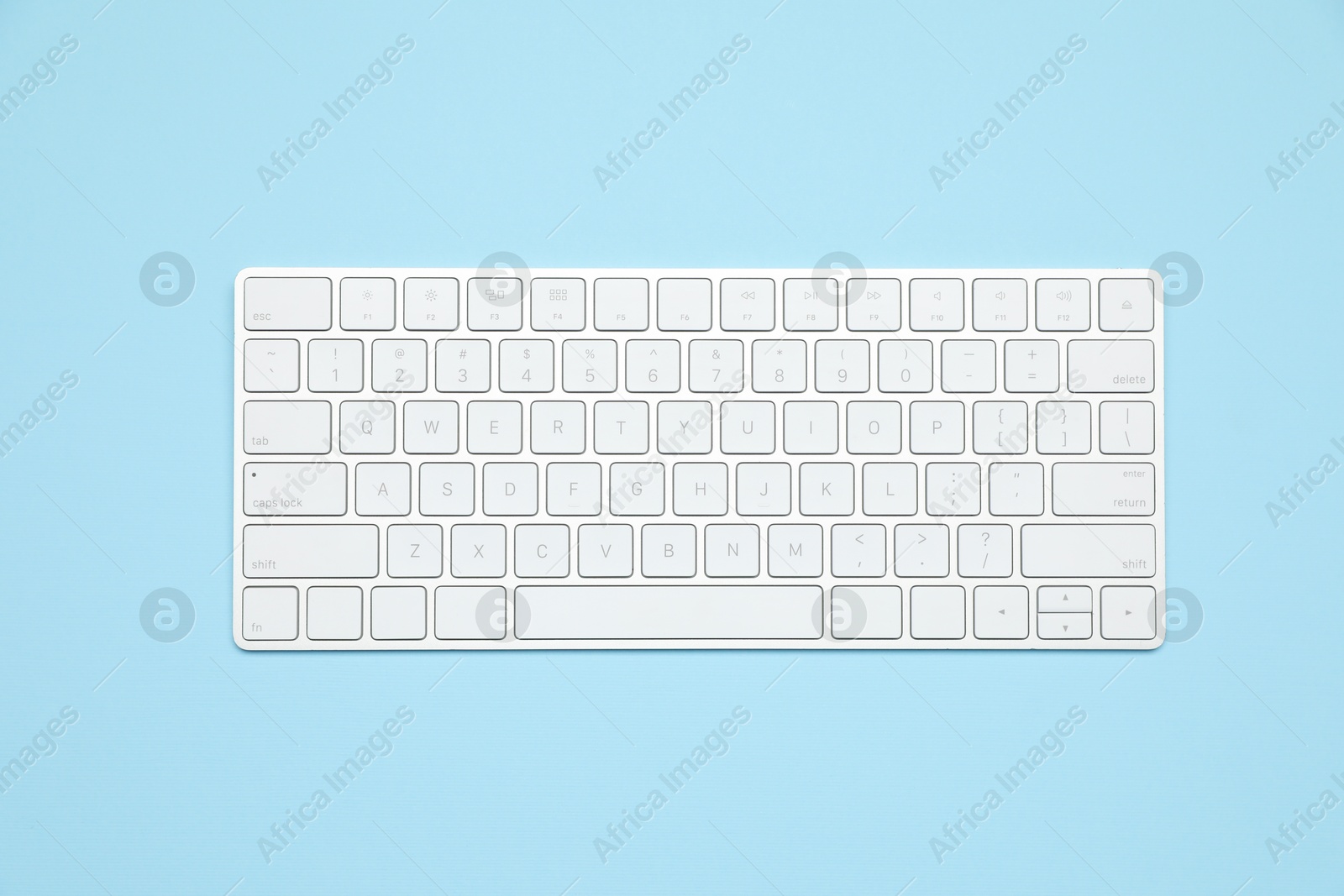 Photo of Modern white wireless keyboard on light blue background, top view