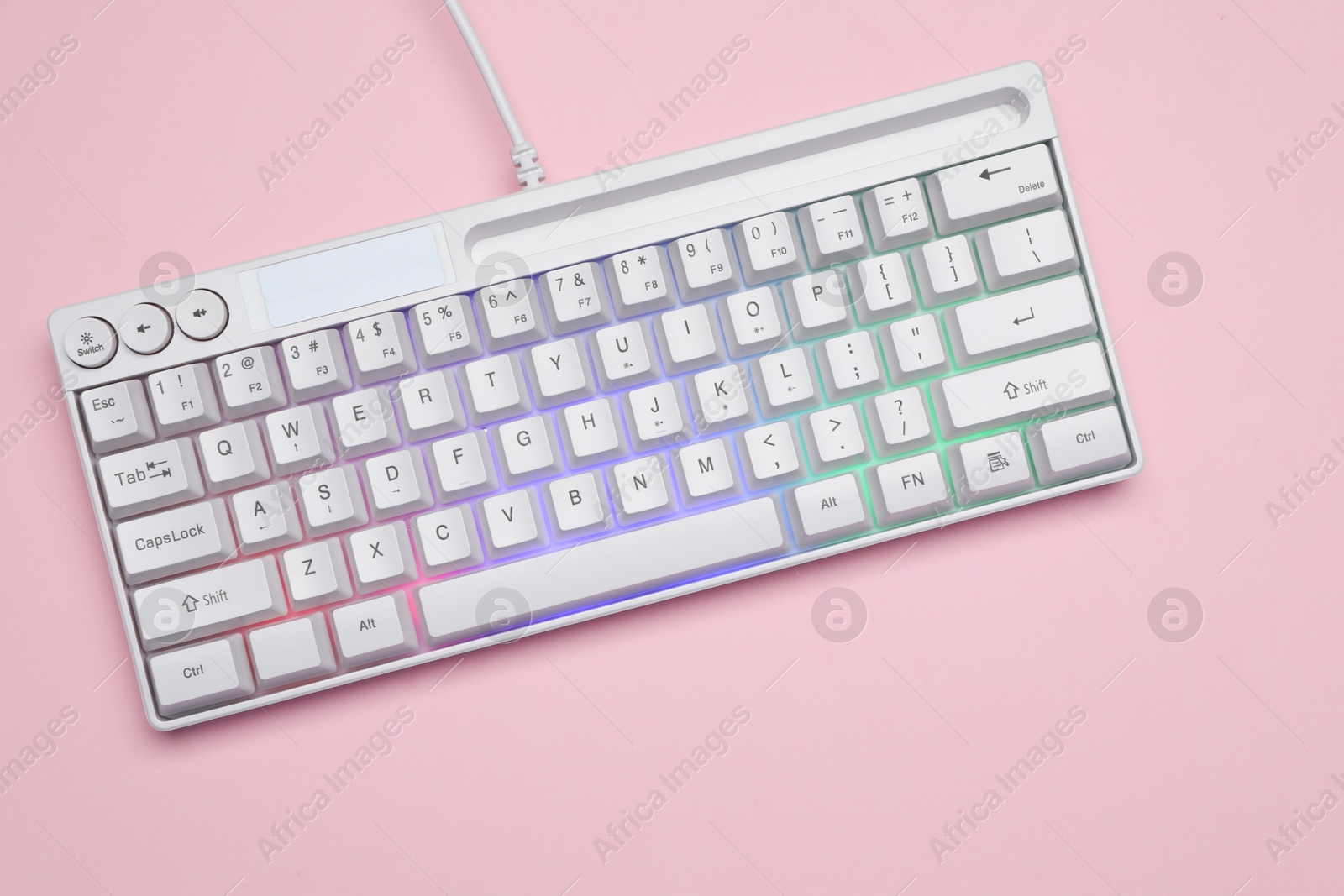 Photo of White keyboard with RGB lighting on pink background, top view. Space for text