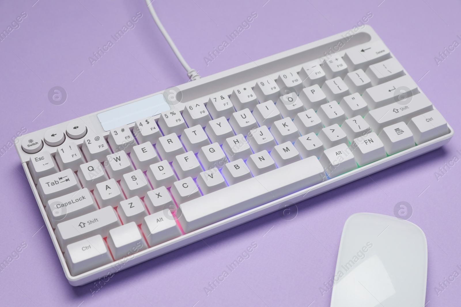 Photo of White keyboard with RGB lighting and mouse on violet background, closeup