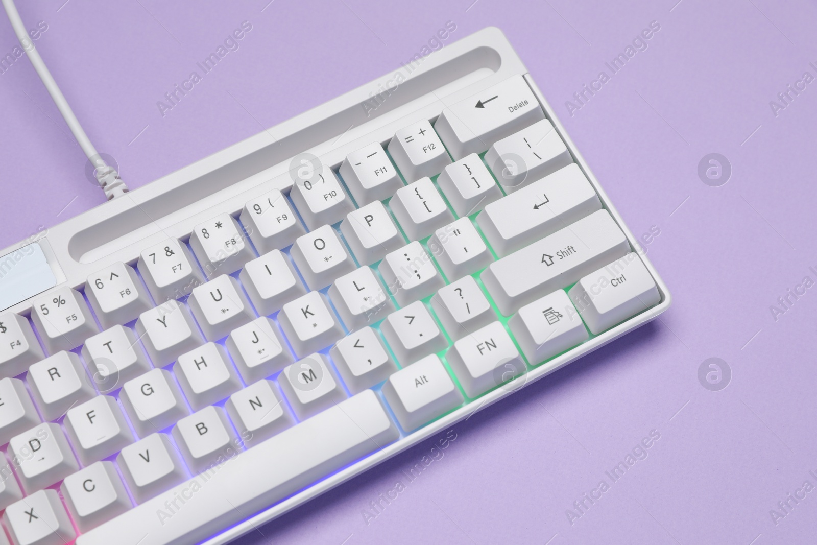 Photo of White keyboard with RGB lighting on violet background, above view